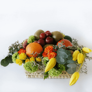 Fruit basket with oranges, tulips, plums, kiwi and flowers