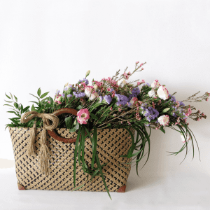 Natural looking flowers eustoma, wax flower, statice and greenery in a basket