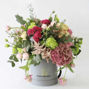 pink, green and peach flowers arranged in a hat box