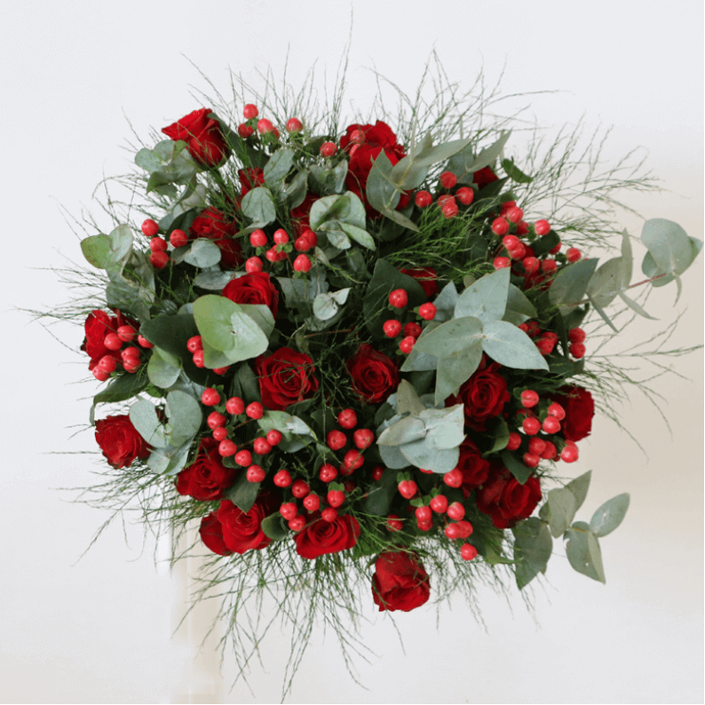Red rose bouquet with a mix of red roses, hypericum and green leaves.