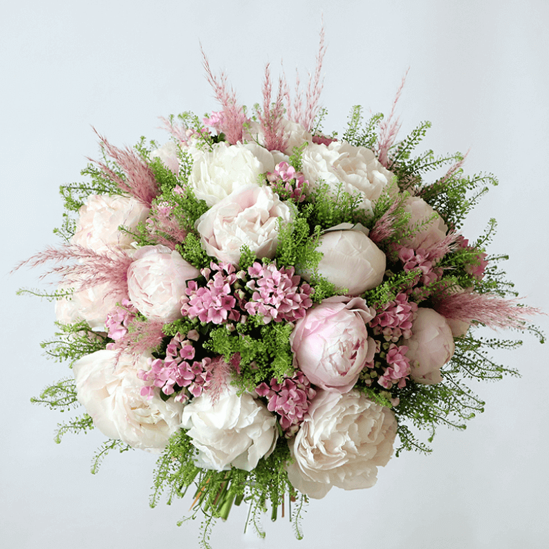 Pink and white peonies with bouvadia in a bouquet with pampas grass