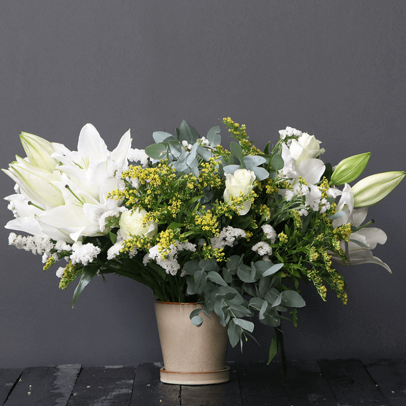 white lily and spray rose with solidago in a ceramic pot