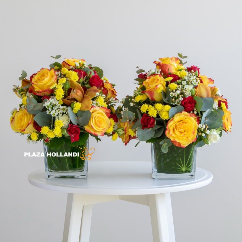 two glass vases full of yellow and red flowers