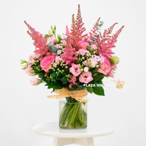 A beautiful bouquet full of mixed pink flowers in a glass vase.